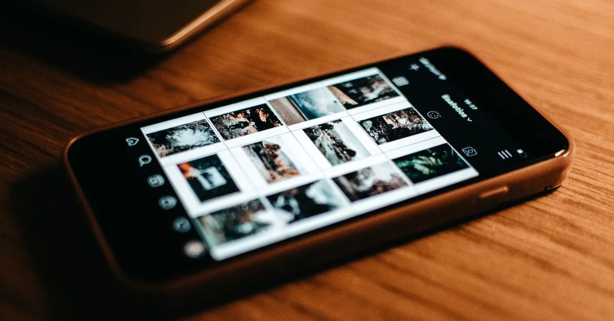 Gros plan d'un smartphone montrant la galerie de photos sur un bureau en bois.