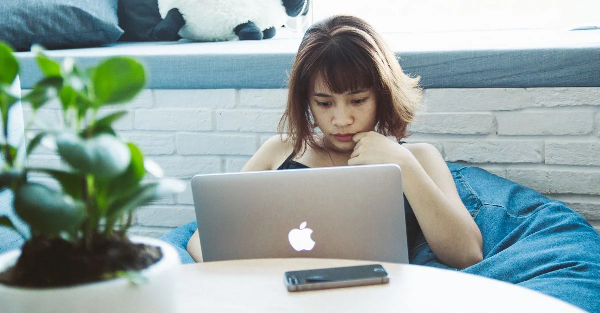 Jeune femme concentrée travaillant sur un ordinateur portable à la maison, adoptant un style de vie de télétravail.