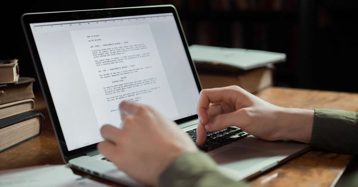 Une personne tapant sur un ordinateur portable dans un espace de travail confortable entouré de livres. Parfait pour les thèmes d'écriture et de technologie.