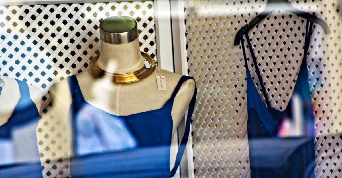 Robes bleues élégantes sur des mannequins dans une vitrine de boutique avec des accessoires à la mode.