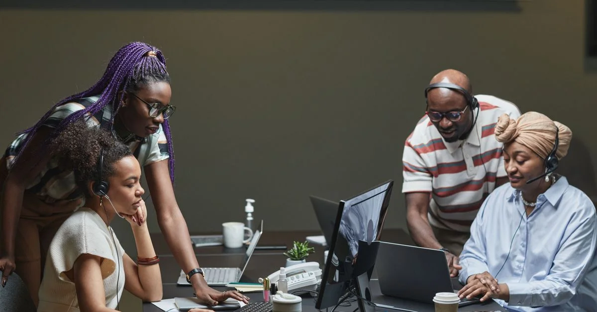 Une équipe diversifiée de professionnels collaborant dans un environnement de bureau moderne, utilisant des casques et des ordinateurs.
